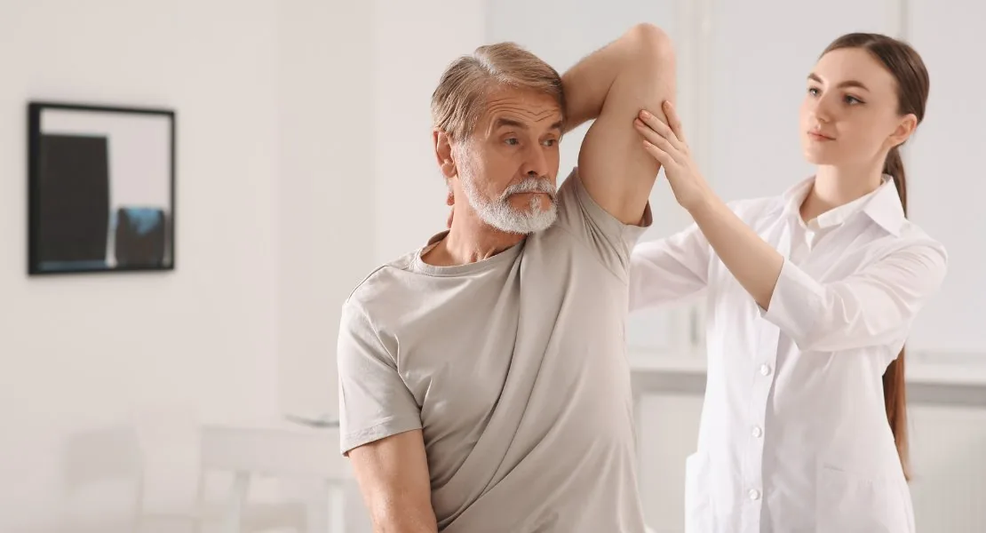 Médico especialista examinando a amplitude de movimento do ombro de um paciente — Clínica Suort, São Paulo